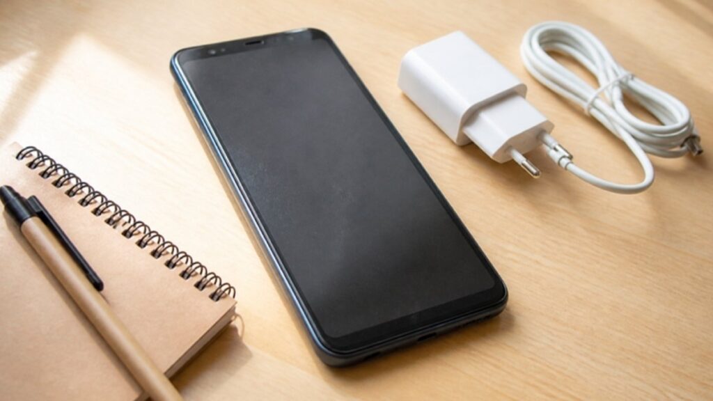 机に置いたスマホと充電器・メモ帳