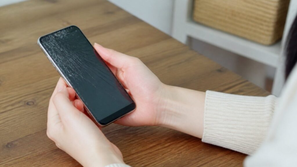 画面が割れたiPhoneを両手で持つ人